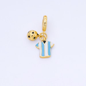 May include: A gold-colored charm featuring a soccer ball and a miniature soccer jersey with blue and white stripes. The charm is designed to hang from a bracelet or necklace, showcasing a sports theme.