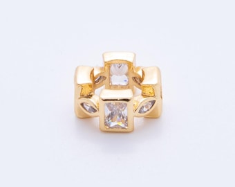 May include: A gold-colored charm with a geometric design. The charm features four rectangular clear stones and four smaller leaf-shaped accents. The charm is set against a white background.