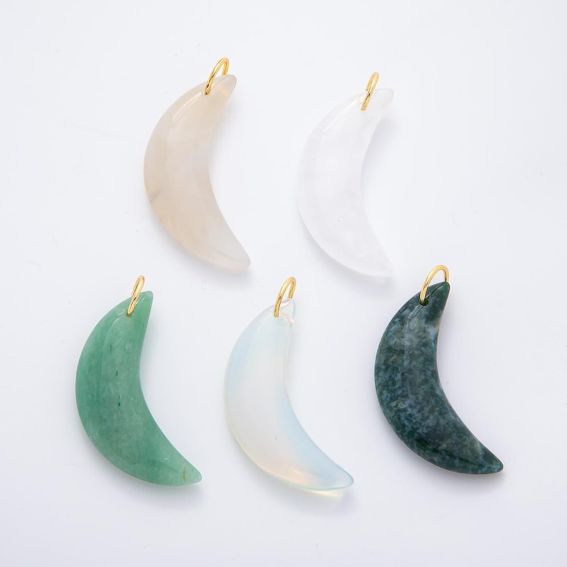 Op de afbeelding: Vijf maanvormige hangers in verschillende kleuren: lichtroze, wit, groen, opalescent en donkergroen, elk met een goudkleurige lus. Deze edelsteenhangers zijn ideaal voor het maken van sieraden.