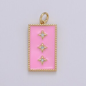 May include: A gold charm with a pink enamel rectangle and three gold stars with clear rhinestones.