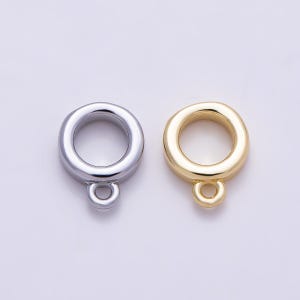 May include: Two circular jewelry connectors, one in a polished silver tone and one in a polished gold tone. Each connector features a thick, smooth outer ring with a smaller, integrated loop at the bottom for attaching additional jewelry components.
