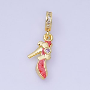 May include: A gold-colored charm in the shape of a high-heeled shoe. The shoe has a red and pink painted design with a small purple gem. The charm's top loop is encrusted with small, clear gems.