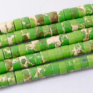 May include: A strand of green and white jasper beads. The beads are round and have a speckled pattern.