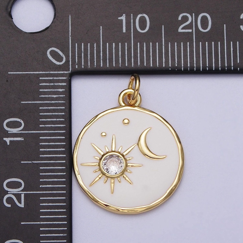 May include: Gold-tone pendant charm with a white enamel circle featuring a sun with a clear rhinestone center, a crescent moon, and three small stars.