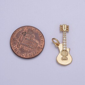 May include: Gold-tone guitar charm with clear rhinestones. The charm is about the size of a US penny.