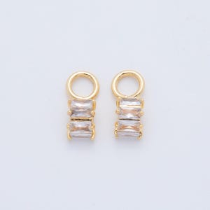 May include: Two gold-colored jewelry findings with clear rectangular crystals. Each finding has a small loop at the top and three stacked crystals below. The findings are set against a white background.