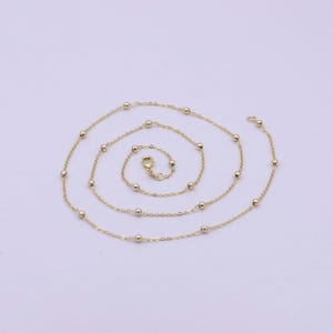 May include: A gold chain necklace with small round beads.