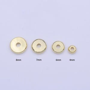 May include: Four gold-colored metal spacer beads in different sizes: 8mm, 7mm, 6mm, and 4mm. The beads are round with a hole in the center.