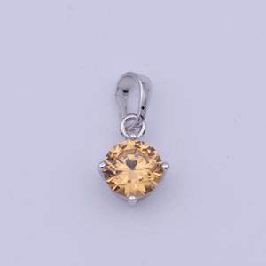 May include: A silver pendant with a round, clear, yellow gemstone.