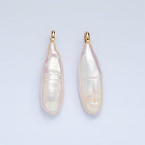 Op de afbeelding: Twee witte barokparels met gouden springringen. De parels zijn onregelmatig van vorm en hebben een parelmoerglans.