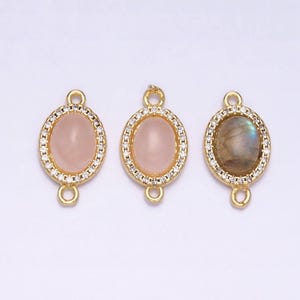 Puede incluir: Tres colgantes ovalados de oro con detalles de cristal transparente. Cada colgante presenta una piedra de color diferente: rosa, blanca y gris.