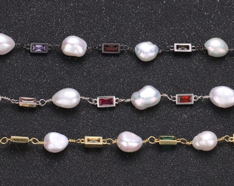 May include: Three pearl necklaces with different colored gemstones. The top necklace has purple gemstones, the middle necklace has red gemstones, and the bottom necklace has green gemstones.