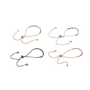 Peut inclure: Quatre bracelets ajustables avec des perles de cristal colorées. Les bracelets sont disponibles en or, argent, noir et or rose.