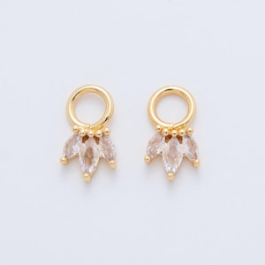 May include: Two gold-coloured earring charms. Each charm features a circular top and a cluster of clear, marquise-cut crystals. The crystals are arranged in a fan shape. The background is plain white.
