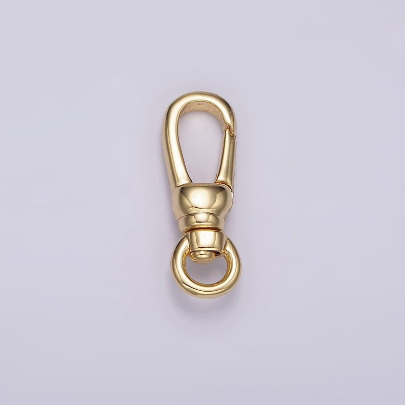 May include: Gold-toned metal swivel clasp with a round ring. The clasp is designed for attaching to a bag or other item.