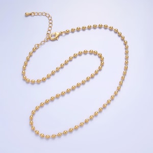 May include: A gold chain necklace with a delicate ball chain design. The chain is made of small, round beads that are evenly spaced.
