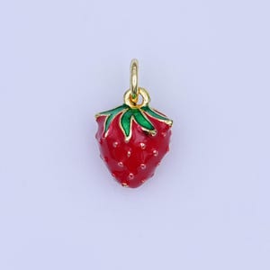 May include: A gold-coloured strawberry charm with red enamel and green leaf details. The charm has a small loop at the top for attaching to a necklace or bracelet. The strawberry has a textured surface.
