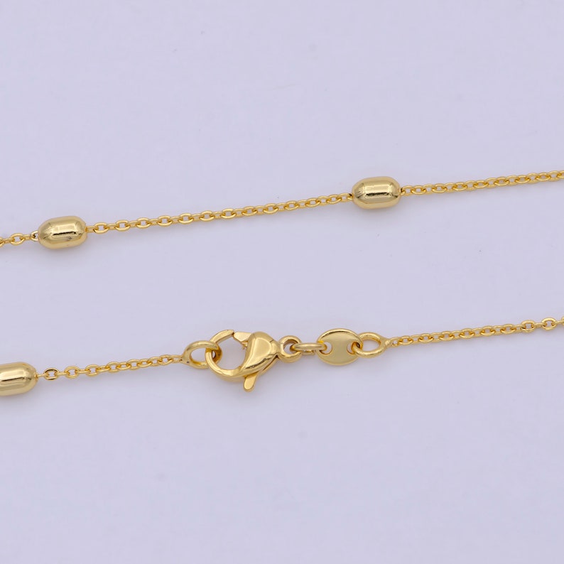 May include: A gold chain necklace with small round beads. The chain has a lobster clasp.