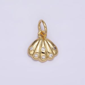 May include: A gold-tone seashell charm with clear rhinestones. The charm has a loop at the top for attaching to a necklace or bracelet.