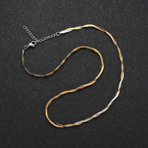 May include: A gold and silver twisted chain necklace with a lobster clasp closure.
