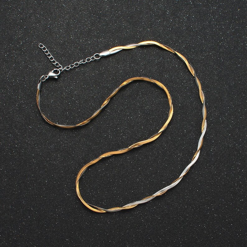 May include: A gold and silver twisted chain necklace with a lobster clasp closure.