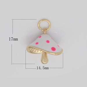 May include: Gold-tone mushroom charm with a white enamel finish and pink polka dots. The charm measures 17 mm in height and 14.5 mm in width.