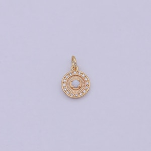 May include: A gold pendant with a white opal stone surrounded by a circle of small clear stones.