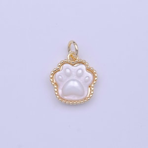 May include: A gold charm with a white paw print design. The charm has a beaded border and a loop for attaching to a necklace or bracelet.
