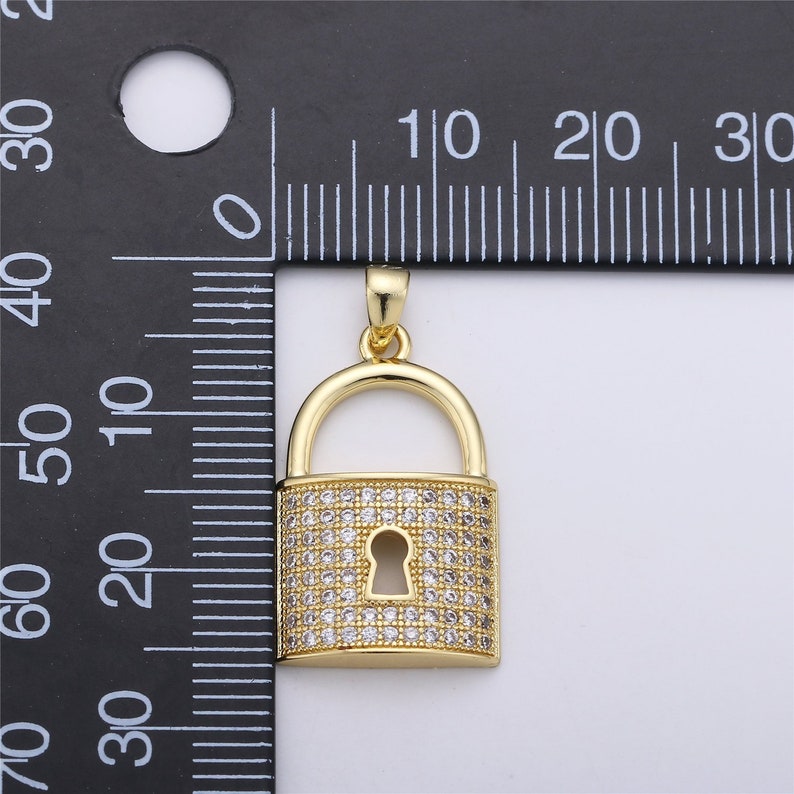 Pu&ograve; includere: Un ciondolo a forma di lucchetto dorato con pietre di zircone cubico trasparenti. Il ciondolo misura circa 2 cm di lunghezza e larghezza.