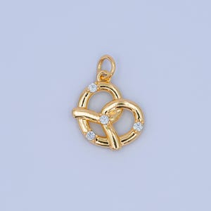 May include: A gold-tone charm in the shape of a pretzel with four clear rhinestones.