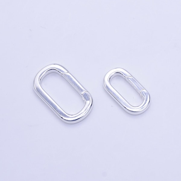 May include: Two silver oval-shaped clasps, one larger than the other. The clasps are made of metal and have a smooth, shiny finish.
