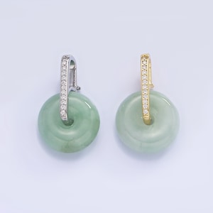 Puede incluir: Un par de pendientes de jade con una piedra redonda de jade y una banda engastada con diamantes. Un pendiente tiene una banda plateada y el otro una banda dorada.
