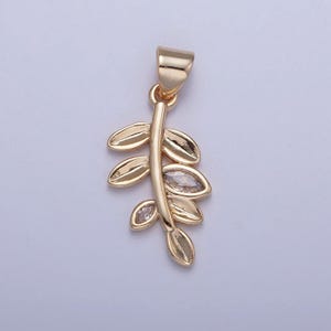 May include: Gold pendant featuring a stylized branch with leaves and clear crystal accents.