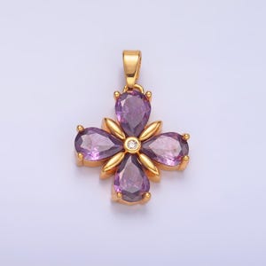 May include: A gold pendant with a four-leaf clover design featuring purple gemstones and a single clear gemstone in the center.