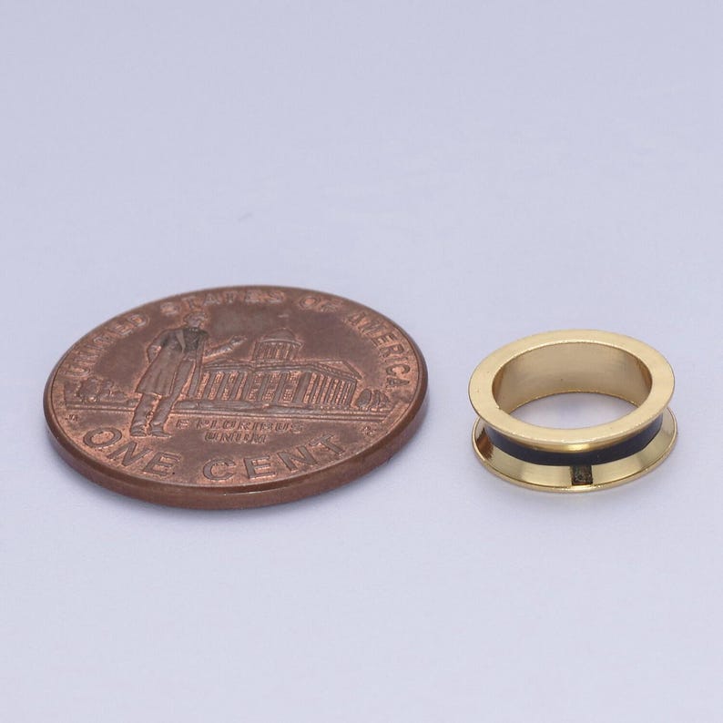 Peut inclure: Une bague en or avec une incrustation noire. La bague est pr&eacute;sent&eacute;e &agrave; c&ocirc;t&eacute; d'un centime am&eacute;ricain pour comparaison de taille.