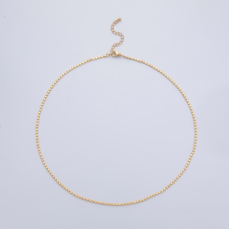 May include: A delicate gold-colored necklace with a series of small, evenly spaced circular beads. The necklace has an adjustable chain and clasp. The jewelry is displayed on a light gray background.