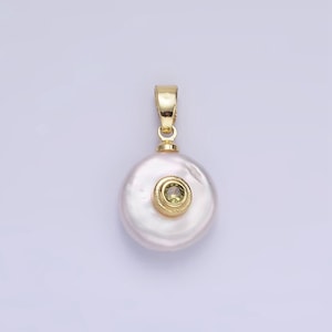 May include: A gold pendant featuring a large white pearl with a small green gemstone set in a gold circle.