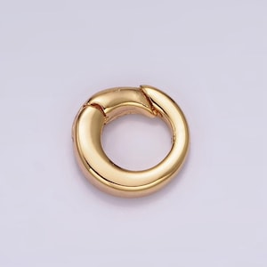 Pode incluir: Um anel de fecho de metal dourado, um tipo de descoberta de joias usado para conectar correntes ou cord&otilde;es.