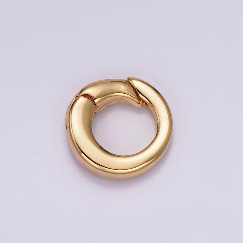 Pode incluir: Um anel de fecho de metal dourado, um tipo de descoberta de joias usado para conectar correntes ou cord&otilde;es.