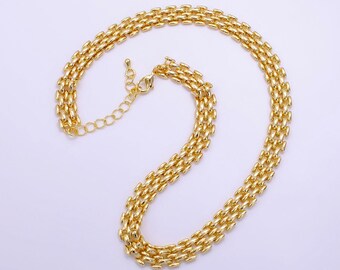 Op de afbeelding: Een gouden ketting met een box chain-ontwerp. De ketting is gemaakt van meerdere rijen met gekoppelde ovale stukken.