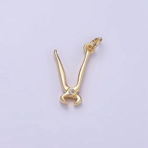 May include: Gold-toned metal charm in the shape of a pair of pliers with a clear rhinestone in the center.