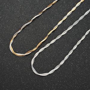 May include: Two twisted chain necklaces, one silver and one gold, on a black background.