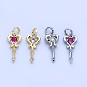 May include: Four key-shaped pendants. Two are gold-toned with a red and clear gem, and two are silver-toned with a clear and red gem. Each pendant has a heart-shaped top and a key-like stem.