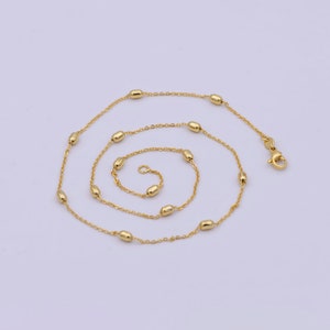 May include: A gold chain necklace with small oval-shaped beads. The chain is delicate and has a lobster clasp.