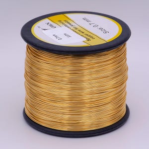 Pu&ograve; includere: Un rotolo di filo di rame color oro per la creazione di gioielli. Il rotolo &egrave; etichettato con "Size: 0.7 mm", "Copper wire for jewelry", "Spectar colour-retaining" e "310m".