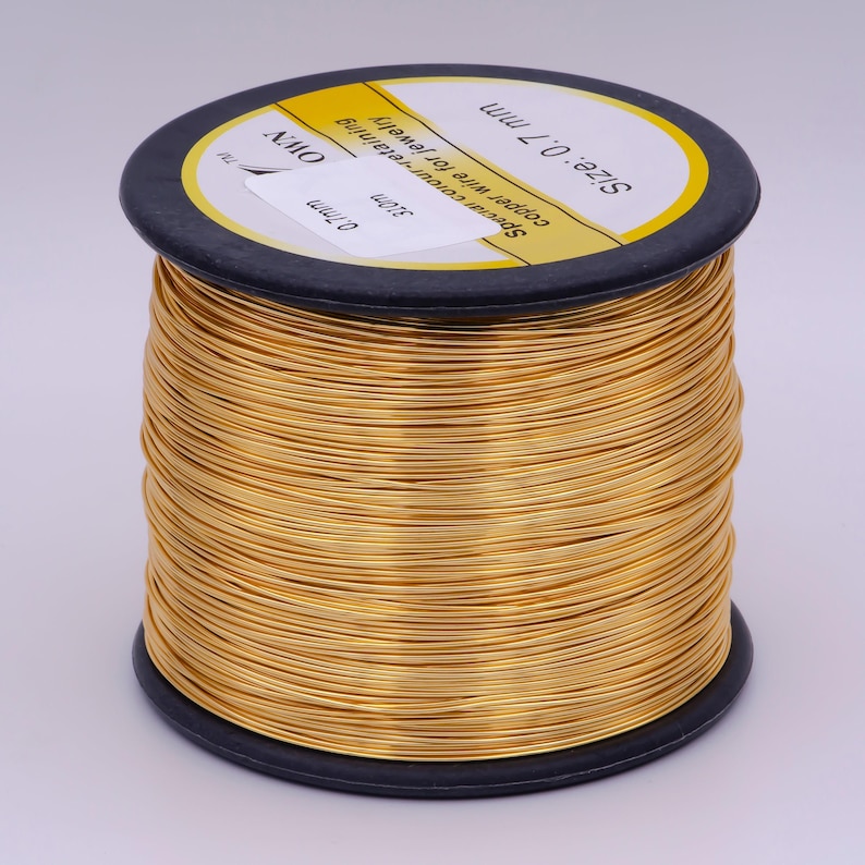 Pu&ograve; includere: Un rotolo di filo di rame color oro per la creazione di gioielli. Il rotolo &egrave; etichettato con "Size: 0.7 mm", "Copper wire for jewelry", "Spectar colour-retaining" e "310m".