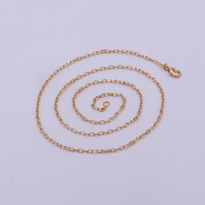 May include: A gold chain necklace with a lobster clasp closure. The chain is made of oval-shaped links.