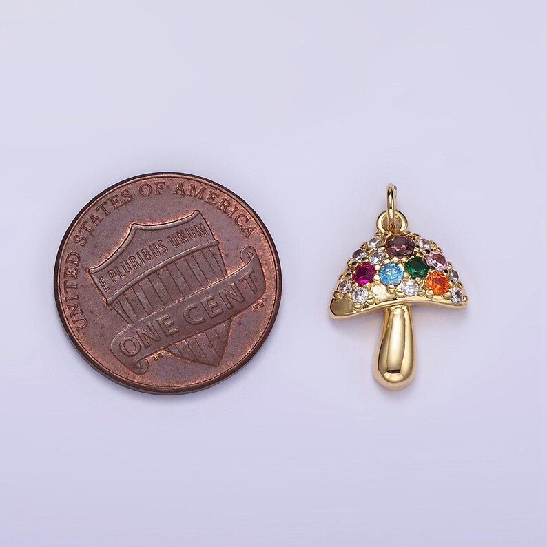 May include: Gold-tone mushroom charm with colorful rhinestones. The charm is about the size of a US penny.