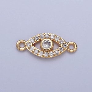 May include: Gold-toned evil eye charm with clear crystal accents. The charm has two loops on either side for attaching to jewelry.