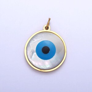 May include: Gold-toned pendant with a blue and black evil eye design on a white mother-of-pearl background.